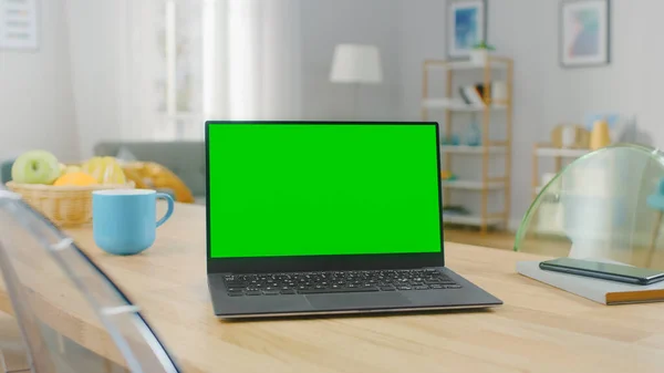 Modern bir dizüstü bilgisayarın Evdeki Ahşap Masa 'da Yatay Yeşil Ekran Mokasıyla Çekimi. Akıllı Telefon Bilgisayarın Yanında Bir Masada Yatar. — Stok fotoğraf