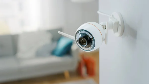 Close Up Object Opname van een moderne Wi-Fi bewakingscamera met twee antennes op een witte muur in een gezellig appartement. Man zit op een bank op de achtergrond. — Stockfoto