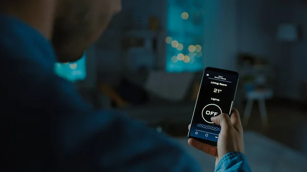 Close Up Colpo di smartphone con applicazione Active Smart Home. La persona sta toccando lo schermo e la luce viene accesa nella stanza. La sua sera accogliente in appartamento. — Foto Stock