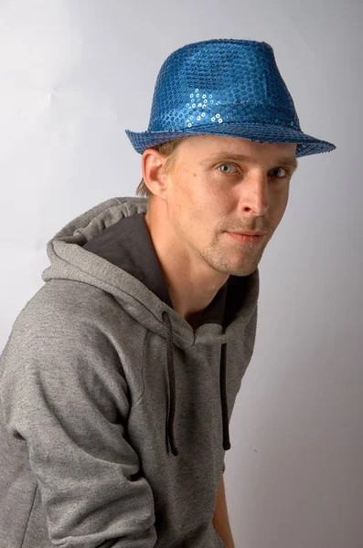 O cara de chapéu azul senta-se em um fundo cinza — Fotografia de Stock
