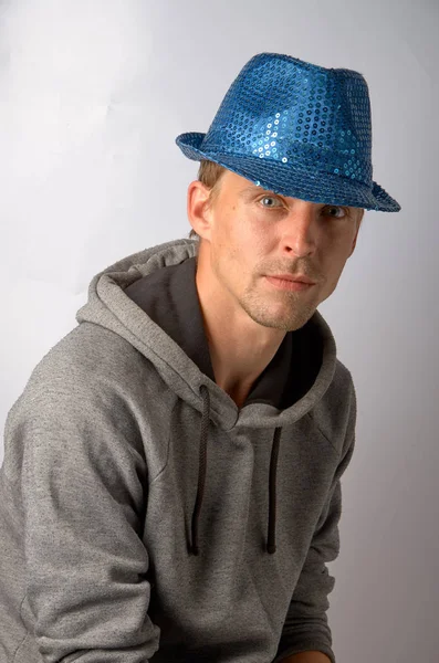 O cara de chapéu azul senta-se pensativo em um fundo cinza — Fotografia de Stock