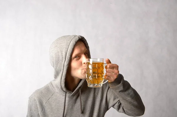 Un joven en una bici gris besa una taza de cerveza fría — Foto de Stock