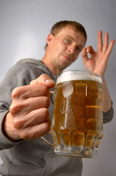 Um jovem elogia uma caneca de cerveja gelada — Fotografia de Stock