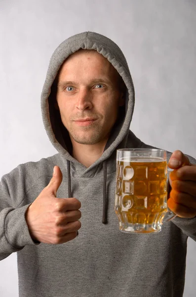 Um jovem elogia uma caneca de cerveja gelada — Fotografia de Stock
