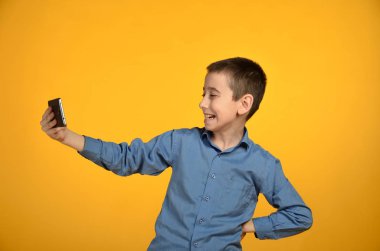 Çocuk sarı bir arka plan üzerinde telefondan kendini bir resim çeker