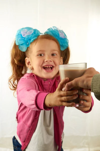 Girl with bows takes a glass of cocoa