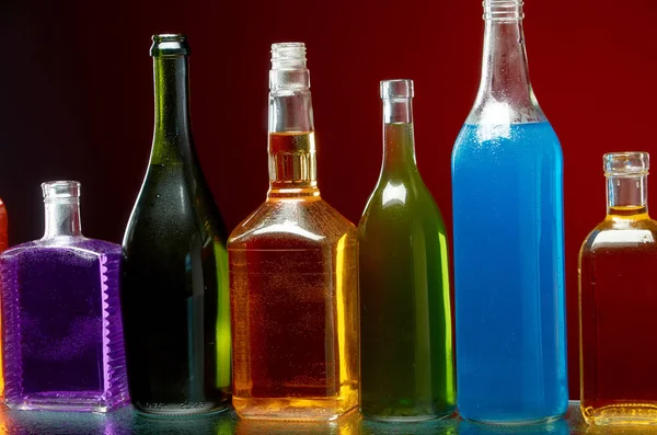 Különböző alkoholtartalmú italok átlátszó üvegben, piros alapon — Stock Fotó