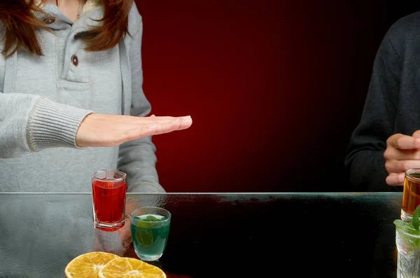 Recusa a oferecer-se para beber álcool com gelo em um vidro transparente em um fundo vermelho — Fotografia de Stock
