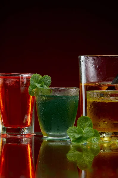 Een prachtige set van alcoholische dranken in glazen met ijs en munt op een rode achtergrond — Stockfoto