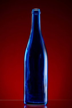 Kırmızı arka plan üzerine koyu cam şişe