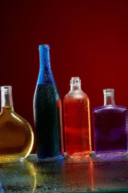 Kırmızı arka plan üzerinde su damlaları alkol şişeleri