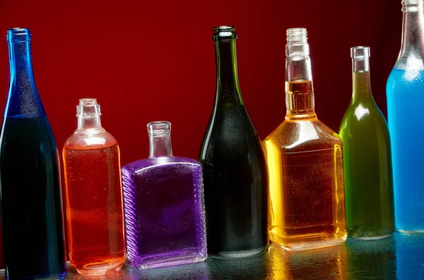Különböző alkoholtartalmú italok átlátszó üvegben, piros alapon — Stock Fotó