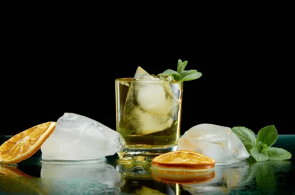 Kyld alkoholhaltig cocktail med is apelsin och färska örter på svart bakgrund — Stockfoto