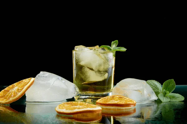 Cóctel alcohólico refrigerado con naranja hielo y hierbas frescas sobre fondo negro — Foto de Stock