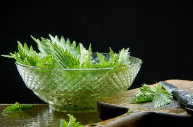 Siyah bir arka planda cam vazo içinde ısırgan salatası