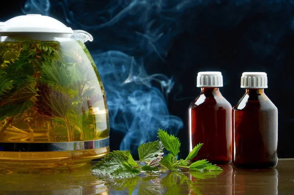 Taze ısırgan ve Isırgan Çayı çaydanlık siyah bir arka planda tıbbi bir ortamda yaprakları — Stok fotoğraf