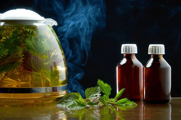 Bule de chá de urtiga fresca e folhas de urtiga em um ambiente médico em um fundo preto — Fotografia de Stock