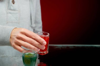 Kırmızı arka planda buz ile çeşitli alkollü kokteyller tatma