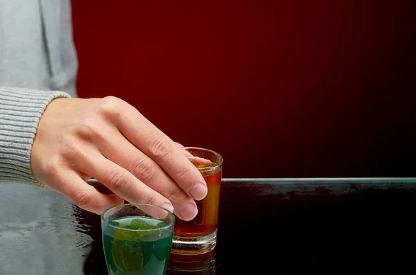 Ochutnávka různých alkoholických koktejlů s ledem na červeném pozadí — Stock fotografie