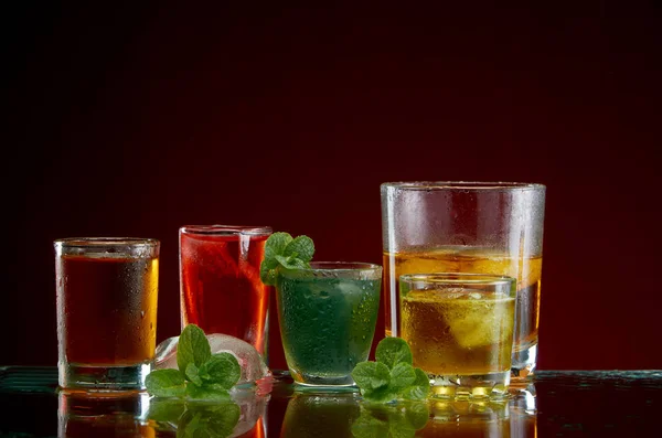 Uppsättning av alkoholhaltiga cocktails med is och mynta på en röd bakgrund — Stockfoto