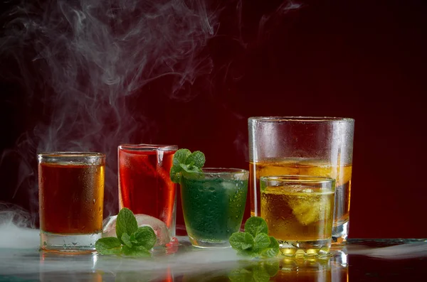 Alcoholic drink with ice and mint in a light smoke on the red background — Stock Photo, Image