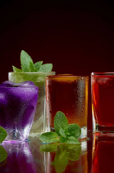 Egy csodálatos sor alkoholtartalmú italok a pohár jég és menta egy piros háttér — Stock Fotó