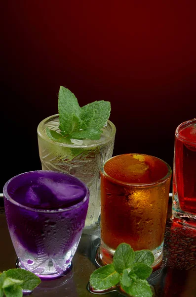 Set van verschillende alcoholische cocktails met ijs en munt op rode achtergrond — Stockfoto