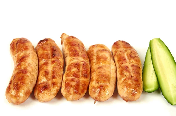 Meat sausages with glitter on a light background. Fried sausage. The concept of traditional cuisine.Sausage with greens and cucumbers Stock Picture