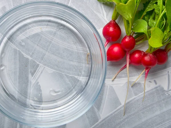 Ein frischer Rettich liegt auf einem hellen Tisch neben Glasschalen — Stockfoto