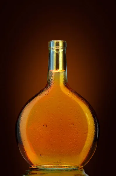 OPEN BOTTLE OF BRANDY WITH DROPS ON GLASS WITHOUT A LABEL ON DARK, JUICY BACKGROUND — Stock Photo, Image