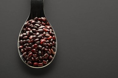 Koyu arkaplan manzaralı kaşıkta kırmızı fasulyeler..