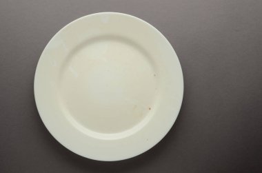 Plaka beyaz boş tozlu seramik yuvarlak gri arka plan üzerinde gölgeler ile.