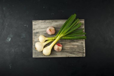 Soğan Sarımsak Tahtada. Dokulu Bir Arka Plan Üzerine Tahta Tahta Üzerine Yatan Sarımsak Başları ile Yeşil Soğan Tüyleri.