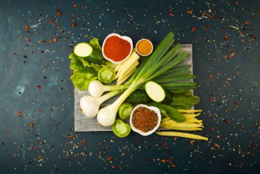 Bir taş arka plan üzerinde ahşap tahta üzerinde sebze. Genç Otlar Soğan Sarımsak Yeşil Fasulye Sarı Mısır Kabak Parlak Baharatlar Bir Dokulu Arka Plan Üzerine Koyu Ahşap Tahta Yalan.