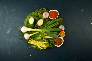 Bir taş arka plan üzerinde ahşap tahta üzerinde sebze. Genç Otlar Soğan Sarımsak Yeşil Fasulye Sarı Mısır Kabak Parlak Baharatlar Bir Dokulu Arka Plan Üzerine Koyu Ahşap Tahta Yalan.