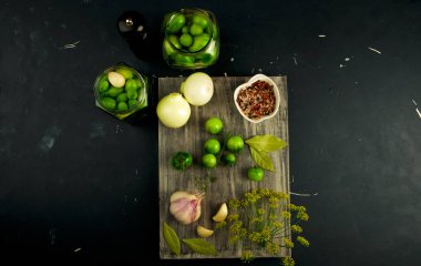 Tahtadaki sebzeli domatesler ve baharatlar. Gri tahta sörf tahtasındaki baharatlı soğanlı sarımsaklı domatesler üzümlü bir taş yüzeyde. Tuzlama GİRİŞ.