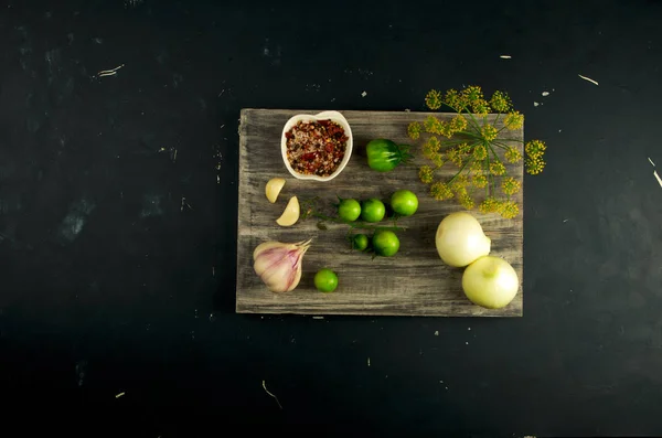 VEGETALES TOMATOS Y ESPECIAS EN EL CONSEJO. Las cebollas GARLIC TOMATOES DILL SPICES EN GRIS BOARD DE MADERA EN UNA SUPERFICIE DE PIEDRA AUMENTADA . — Foto de Stock