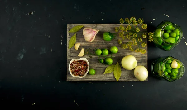 VEGETALES TOMATOS Y ESPECIAS EN EL CONSEJO. Las cebollas GARLIC TOMATOES DILL SPICES ON GREY WOODEN BOARD ON A RaISED STONE SURFACE. EL CONCEPTO DE LA SALTACIÓN. — Foto de Stock