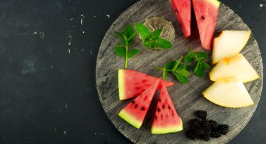 Kavun Karpuz Böğürtlen Ve Arka Planda Nane. Olgun Blackberries Nane ile Olgun Karpuz Sulu Kavun Üç Adet Karanlık Bir Arka Plan Üzerine Ahşap Bir Tahta Üzerinde Yalan.