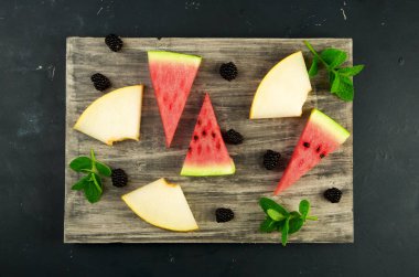 Kavun Karpuz Böğürtlen Ve Arka Planda Nane. Olgun Blackberries Nane ile Olgun Karpuz Sulu Kavun Üç Adet Karanlık Bir Arka Plan Üzerine Ahşap Bir Tahta Üzerinde Yalan.