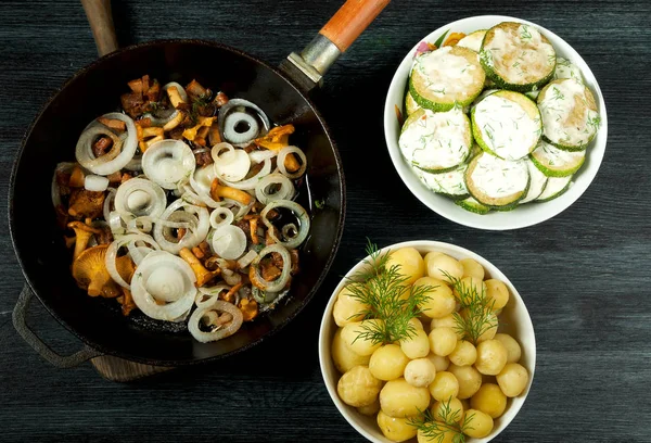 Legumes em segundo plano. Molho de abobrinha frito em uma chapa. As batatas fervidas jovens com endro em um boliche. Cogumelos chanterelle fritos com cebolas de ouro em uma panela de ato de fritar. espaço de cópia — Fotografia de Stock