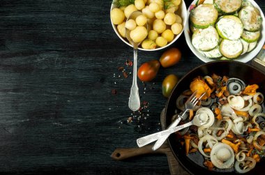 Arka planda sebzeler var. Bir tabakta kızarmış kabak sosu. Bir kase dereotu ile genç haşlanmış patates. Tavada altın soğan ile kızarmış chanterelle mantar. kopyalama alanı