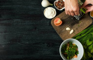 Sebzeli salata. Yukarıdan görüntüleyin. Koyu renkli bir arka plandaki tabakta taze salata. Sarımsak, domates, salatalık, dereotu ve soğan koyu yüzeybir tabak. Kopyalama alanı.