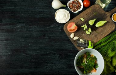 Sebzeli salata. Yukarıdan görüntüleyin. Koyu renkli bir arka plandaki tabakta taze salata. Sarımsak, domates, salatalık, dereotu ve soğan koyu yüzeybir tabak. Kopyalama alanı.