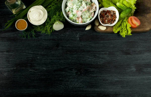 Ensalada con verduras. Vista desde arriba. Ensalada fresca en un plato sobre un fondo oscuro. Ajo, tomate, pepino, eneldo y cebolla en un plato de superficie oscura. Copiar espacio . — Foto de Stock