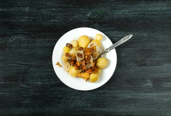 Verduras en el fondo. Patatas jóvenes hervidas con eneldo en un tazón con champiñones chanterelle fritos con cebolla dorada sobre un fondo oscuro. espacio de copia . — Foto de Stock