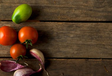 Arka planda domatesler var. Domates, sarımsak tahta bir yüzeyde. Yukarıdan görüntüleyin. Taze sebzeler. kopyalama alanı.