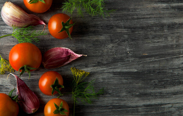 Tomatoes on the background. Tomatoes, garlic on a wooden surface. View from above. Fresh vegetables. copy space.