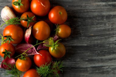 Arka planda domatesler var. Domates, sarımsak tahta bir yüzeyde. Yukarıdan görüntüleyin. Taze sebzeler. kopyalama alanı.