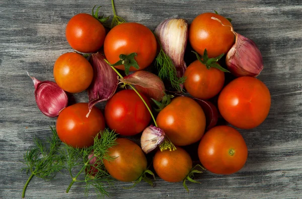 Tomatoes on the background. Tomatoes, garlic on a wooden surface. View from above. Fresh vegetables. copy space. — Stock Photo, Image
